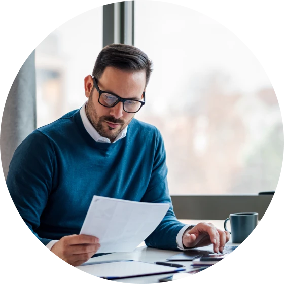 Man in business casual attire seated at table looking over paperwork